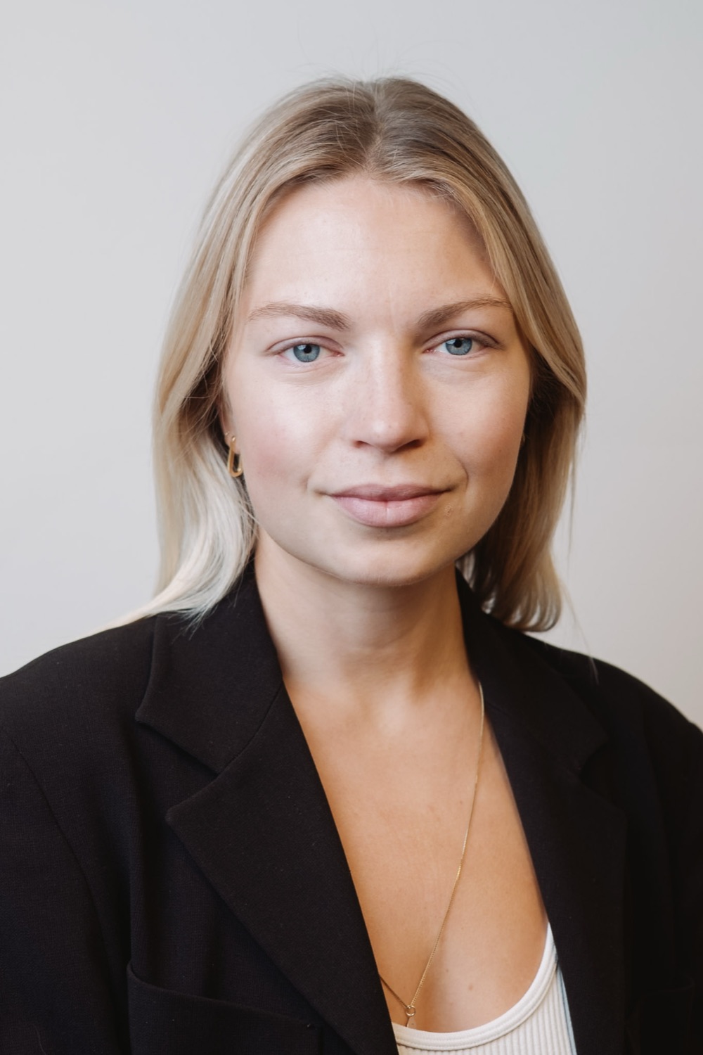 Team headshot in a dark blazer, neutral backdrop, London